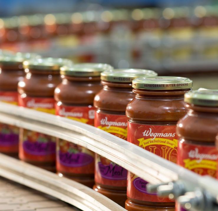 Plastic jars of tomato sauce on conveyor